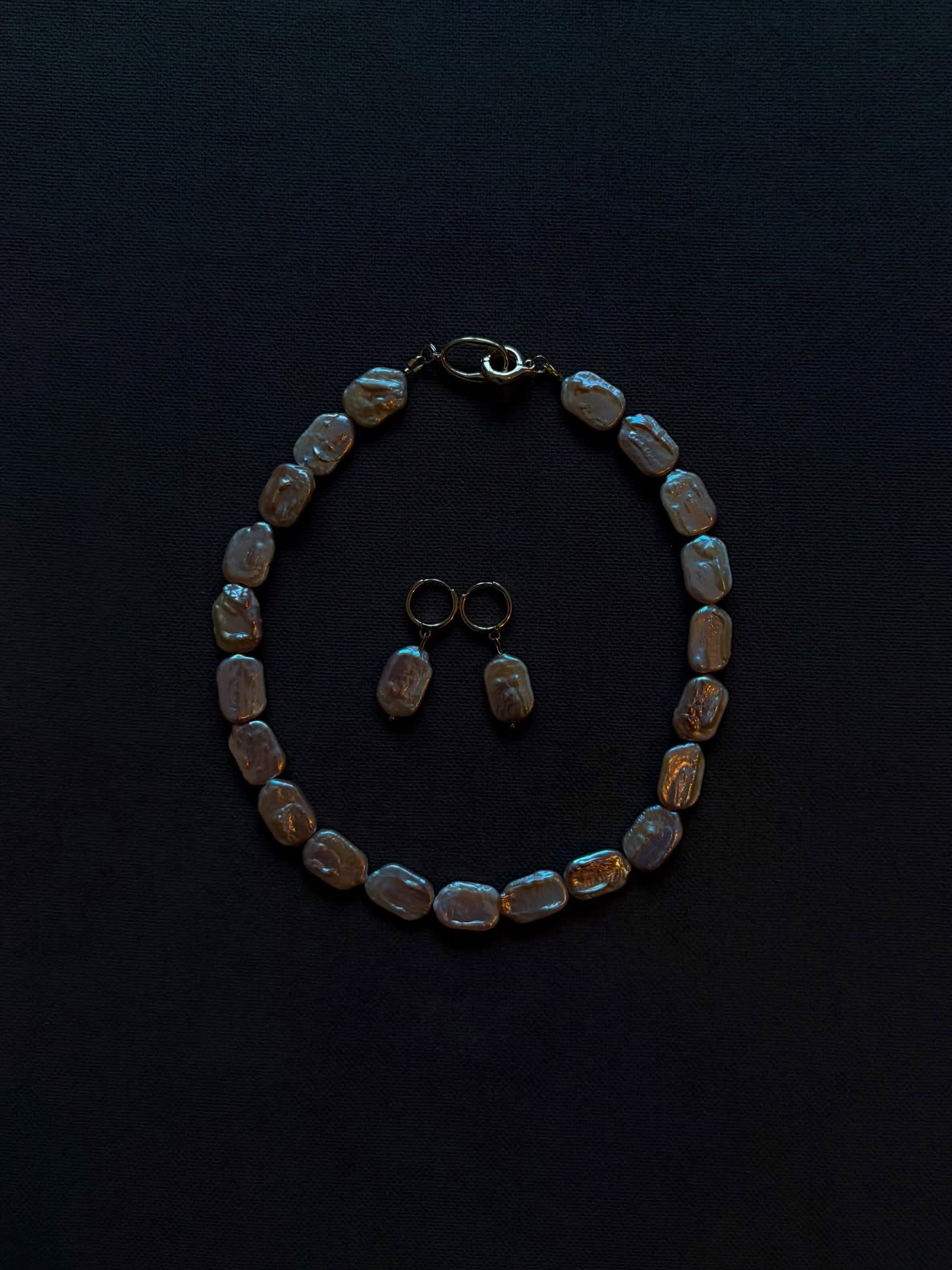 Pearl necklace and earrings set on dark background