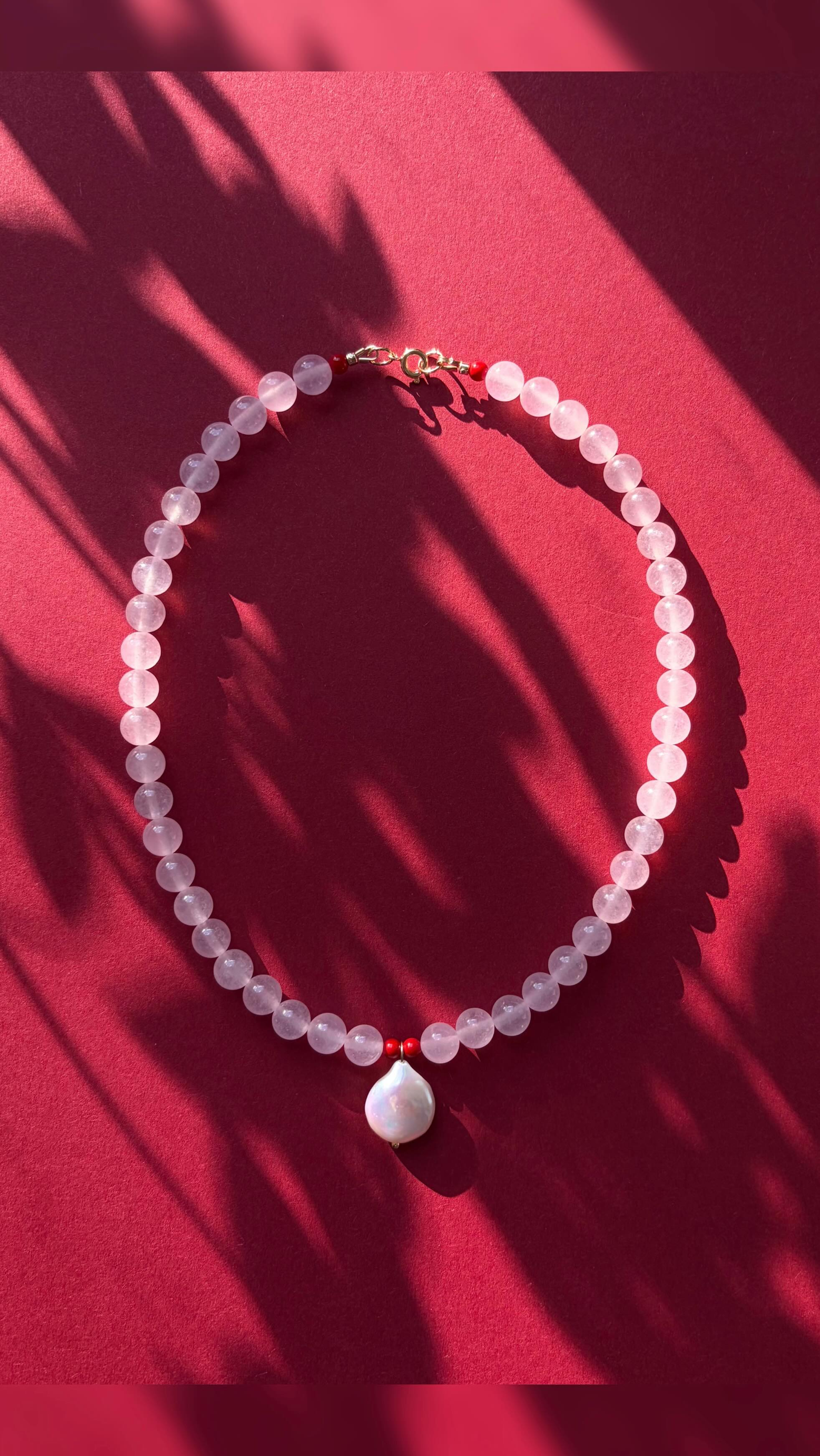 Rose quartz necklace with pearl pendant on pink background
